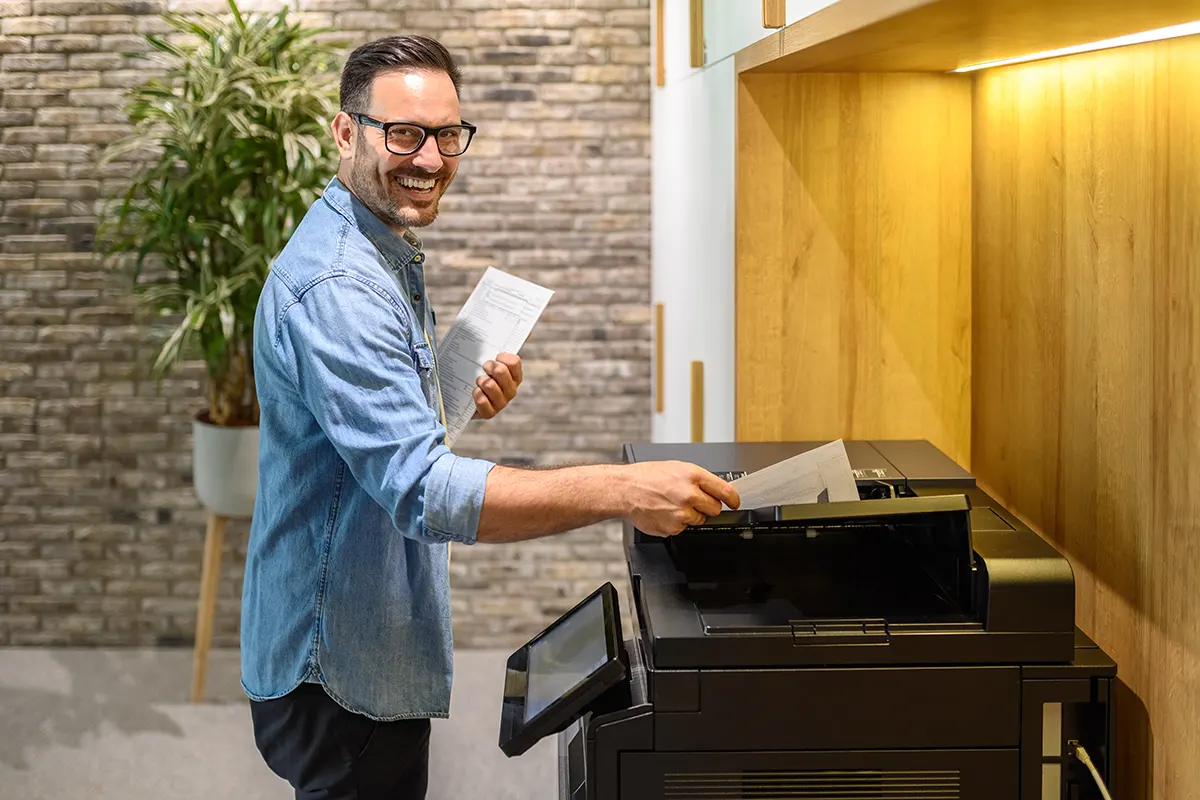 A business professional printing reports using an advanced copier, optimising workflow and improving workplace efficiency.
